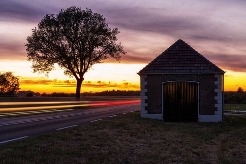 Koesthuis aan de dijk bij Deventer en Olst met verkeer op de achtergrond in de avond