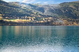 Autumnal lake with reflection and colourful forest under blue sky