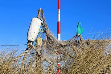Nature morte sur la plage avec des déchets / des articles de plage par un vieux filet de pêche sur Ans Houben