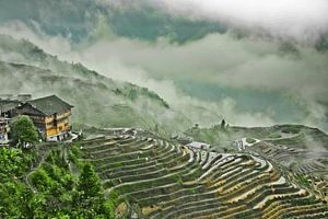 huis op de heuvel is een heuvel van wolken en mist. Mistig herfstlandschap met rijstterrassen. China van Michael Semenov