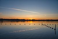 Zonsopkomst bij een meer en boeien.