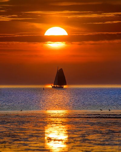 Zonsondergang en zeilboot bij Harlingen tijdens eb