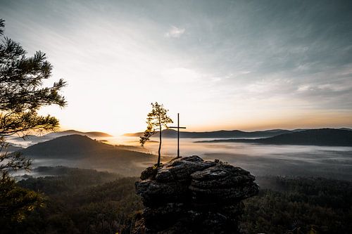 Landschap met mist, rotsen en kruis in zonsopgang