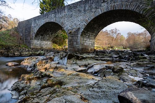 Kleiner Wasserfall unter einer Steinbrücke