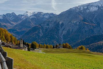 Kerkje van een bergdorp in de herfst met besneeuwde bergtoppen
