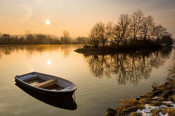 Broken rowboat anchored on riverbank on cold winter morning by Robert Ruidl
