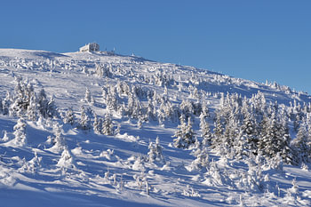 A mountain hut on a snow-capped peak under a clear sky