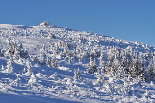 A mountain hut on a snow-capped peak under a clear sky