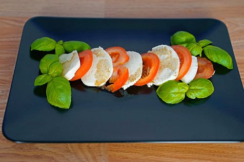 Tomaat, basilicum en mozarella met balsamico op een zwart dienblad
