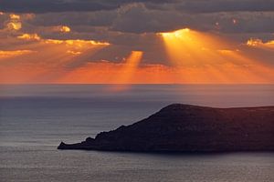 Sonnenuntergang am Meer mit Strahlen und Inselsilhouette