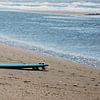 Blaues Surfbrett am Meer von Blond Beeld