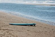 Blauwe surfplank aan zee van Blond Beeld thumbnail