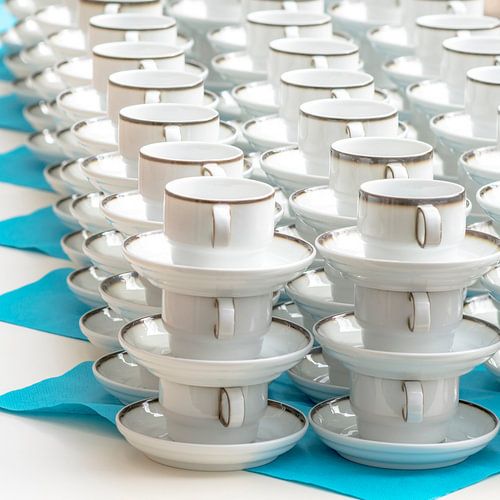 Witte koffiekopjes met bordstandaard op een rijtje gestapeld