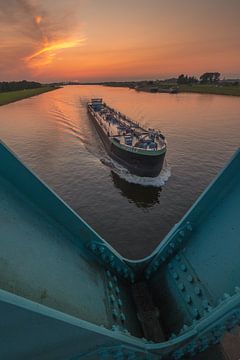 Binnenvaartschip bij sluis tijdens zonsondergang