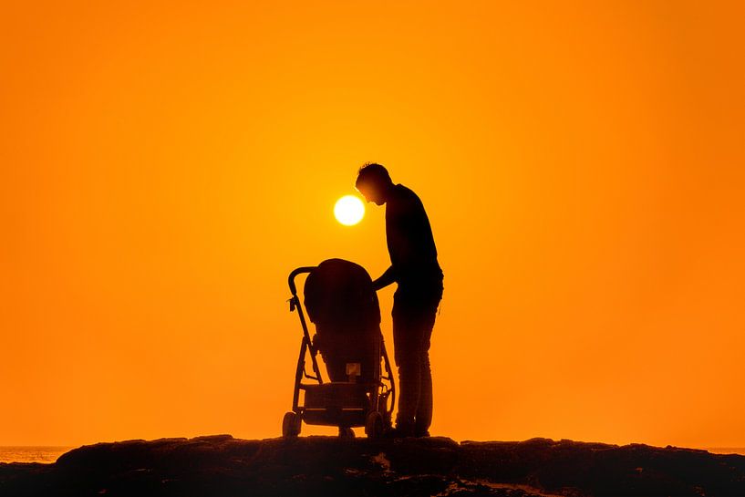 Man buigt zich over kinderwagen tijdens zonsondergang van Harrie Muis