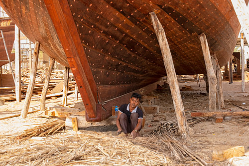 Un homme travaille à la construction d'un boutre en bois à Oman