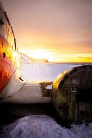 Wrack einer DC-3 in einer verschneiten Landschaft bei Sonnenuntergang, Eyvindarholt, Island von René Wiegmink