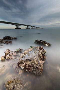 Stones in the water at the Zeeland Bridge by Yvonne van Leeuwen