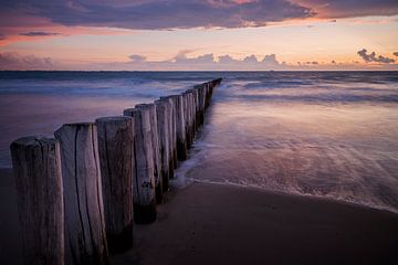 Rangée de poteaux dans un coucher de soleil pastel sur la côte zélandaise sur Krijn van der Giessen