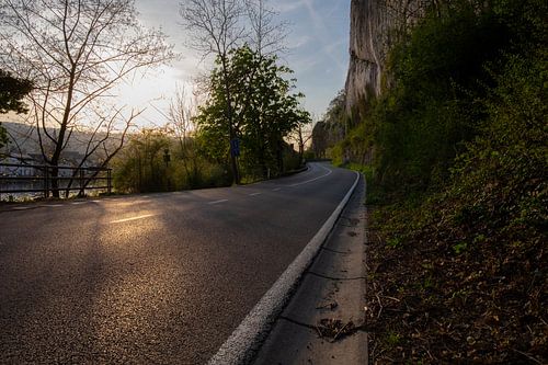 Evening light on a deserted road with a rock face next to it