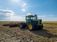 Grüner John Deere Traktor auf einem bewirtschafteten Acker