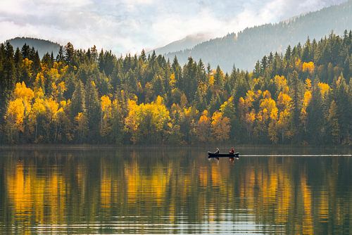 Bomen in herfstkleuren met roeiboot op spiegelend meer in Canada