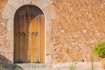 Vieille porte d'entrée en bois et mur de pierre en arrière-plan d'une maison rustique