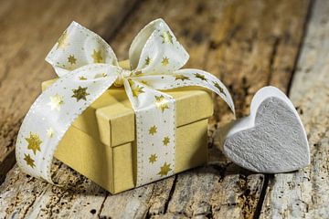 Kerstcadeau met strik in de vorm van een witte gouden ster en een klein hartje op hout van Alex Winter