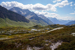 Sommerliche Berglandschaft in der Schweiz mit grünen Almen und markanten Gipfeln.