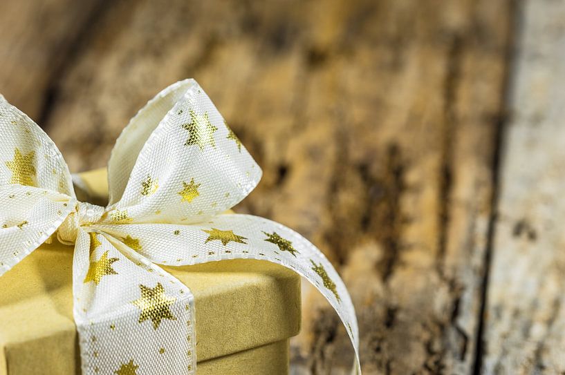 Christmas present with golden star shaped ribbon bow by Alex Winter