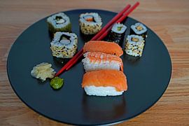 Sushi auf einem Teller mit Stäbchen angeordnet