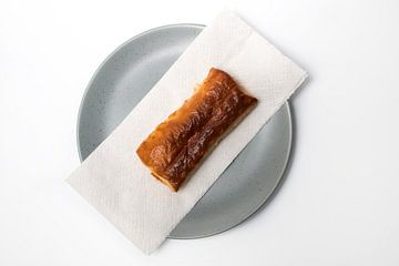 Warm sausage roll on a plate. by N. Rotteveel