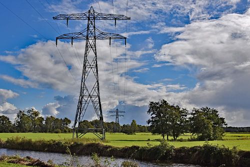 Coulisselandschap met hoogspanningsmasten en een prachtige wolkenlucht.