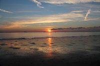 Kleurrijke zonsondergang met reflectie op strand