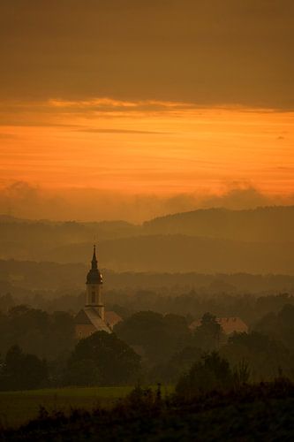 Oranje lucht boven een dorp met een kerk