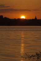 Zonsopkomst aan het water met het silhouet van een kerkje