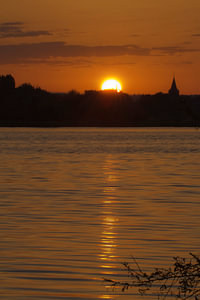 Sonnenaufgang an der Uferpromenade mit der Silhouette einer Kirche