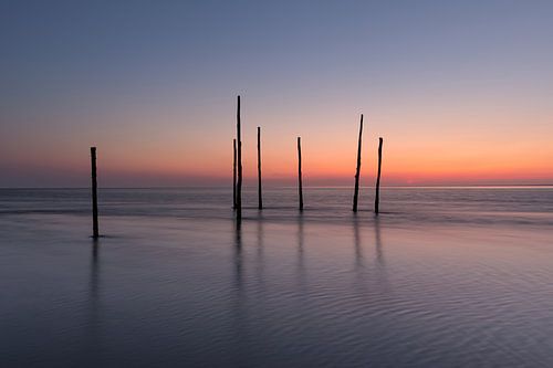 Serene calm at fishing poles on the mud flats