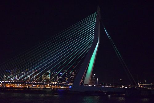 Gekleurde Rotterdamse Erasmusbrug in de nacht met de stad als achtergrond