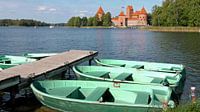 Zicht op het Trakai kasteel met op de voorgrond kleurrijke roeibootjes aan een steiger