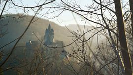A castle shrouded in mist, nestled amongst the mountains, awakens in the morning light