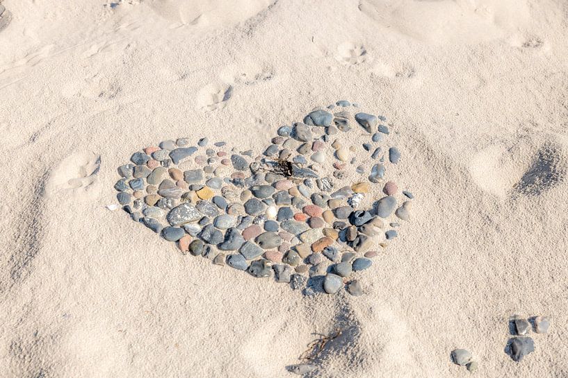 Herz aus Kieselsteinen auf einem Strand mit Hundespuren teilweise mit Sand überdeckt von Hans-Jürgen Janda