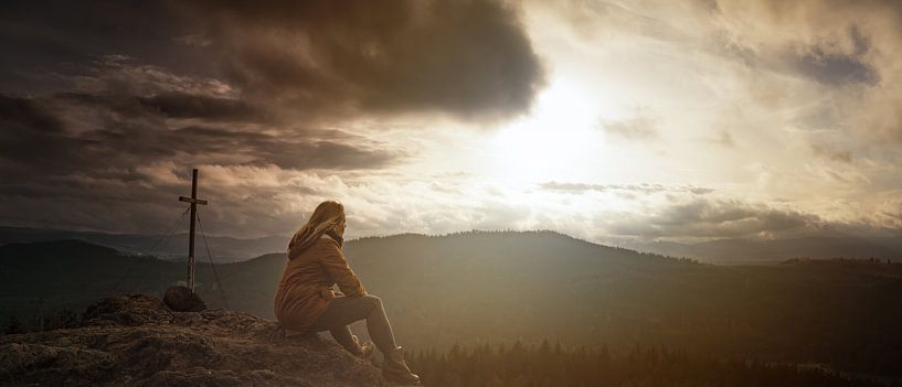 Vrouw op bergtop met kruis in dramatische lucht van Jonas Weinitschke
