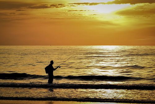 Visser aan zee bij zonsondergang