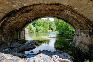 Stenen brug over een rustige rivier omgeven door weelderig groen in spanje van ChrisWillemsen