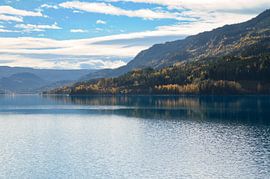 Autumnal lake with reflection and colourful forest under blue sky