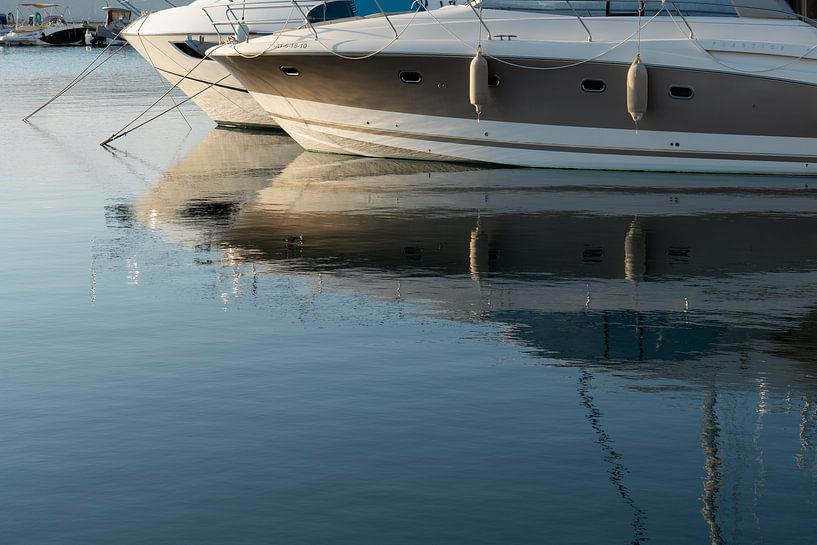 Boats are reflected in calm sea water 1 by Adriana Mueller