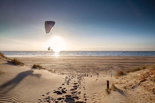man paragliding op strand bij zonsondergang in de zomer