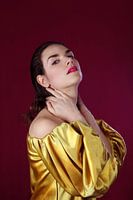 Portrait d’une femme en blouse dorée sur fond rouge