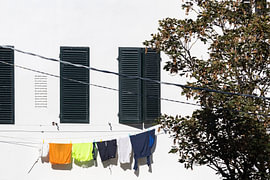 Wäscheleine mit Wäsche, die an einem denkmalgeschützten Gebäude in Lucca, Toskana, Italien, zum Trocknen aufgehängt ist. von André Blom Fotografie Utrecht
